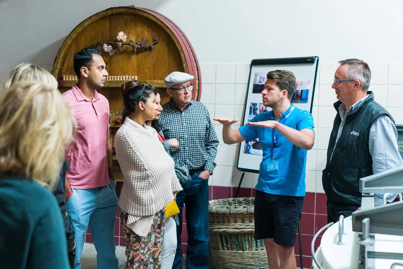 A guide explaining Champagne production to the group in front of a large wooden cask