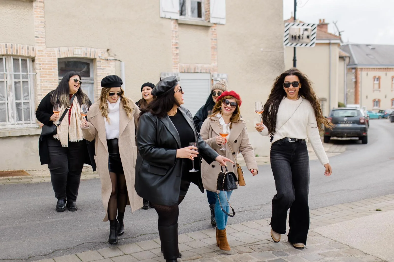 Tour guests walking a village street in the Champagne region, glasses in hand