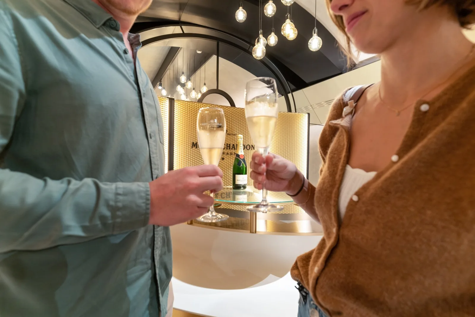 Two guests holding flutes at a lit Moët & Chandon tasting counter