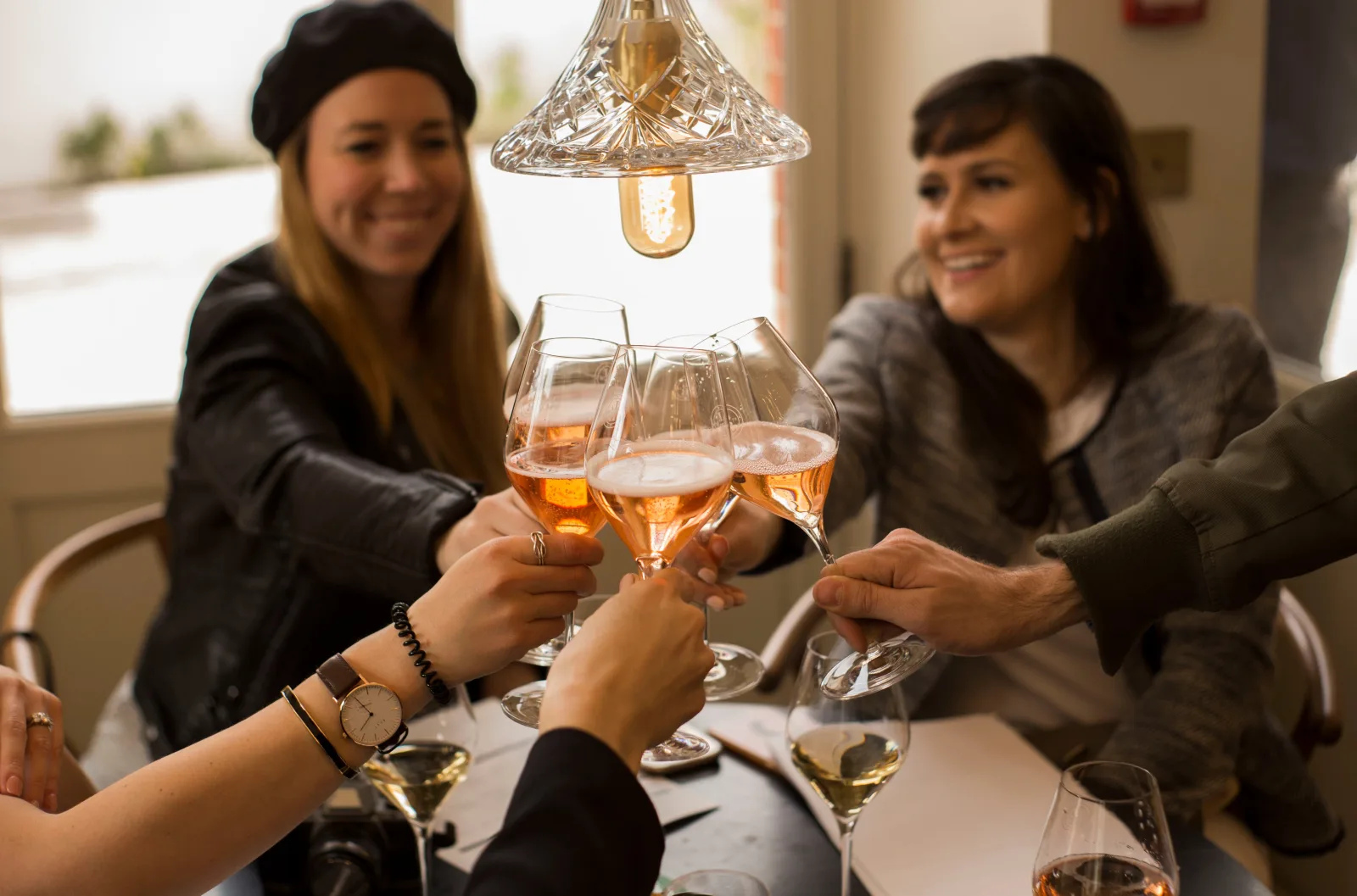 Guests clinking glasses of rosé Champagne across a table indoors