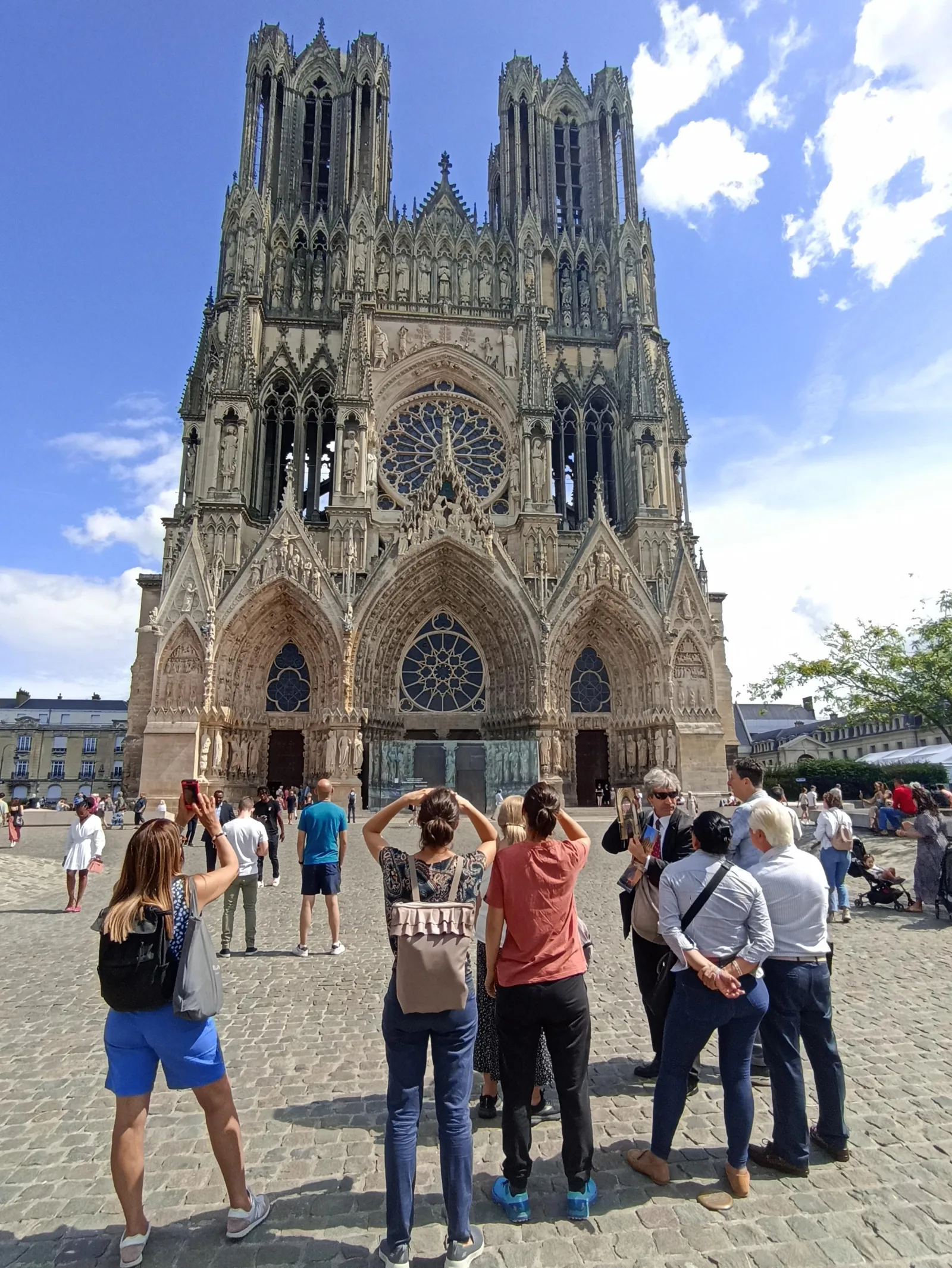 Visitors gathered in front of the twin-towered west facade of Reims Cathedral